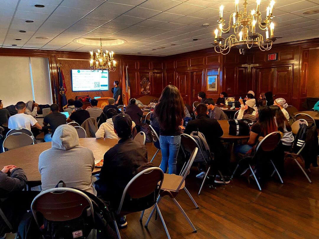 Students gathered in an event venue viewing a presentation from the presenter.